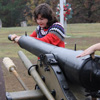 Priscilla Porter swabs out the barrel of a just-fired cannon at a Phi Alpha Theta-sponsored community service project at Britton Lane Battlefield on November 3, 2015. Emily Littleton (arm on the right), wearing an artillery thumbstall, covers the barrel vent to prevent hot ashes or other residue from blowing up the vent and causing a risk to everyone around the cannon.