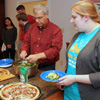 Attendees at the Phi Alpha Theta Best Chapter Award pizza party at Dr. Carls's home on October 21, 2016, go through the food line. They are (starting at the left rear and moving forward) Robert Briley, Katherine Cheshire, Stephen Lewoczko, Seth Reid, Dr. David Thomas, and Susannah Murphine. Party hostess Dr. Alice-Catherine Carls is on the left, while Jordan Sellers (dressed in a light green shirt with a pink logo) has her back to the camera.