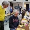 Rotarian James Orman (standing), Dr. Stephen Carls (seated on left) and Seth Reid (seated on the right) enjoy a bit of laughter on March 18, 2017, after Carls explained how a syrup dispenser he was using on his pancakes malfunctioned.