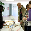 Dr. Stephen Carls (center, wearing jacket) inspects the arrangement of food items while Katherine Cheshire (left) makes a sale at the Franco-American bake sale on April 11, 2018. Photo by Kristi Woody
