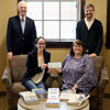 Delta-Psi Chapter President Lauren Butler (seated, left) presents a Phi Alpha Theta Best Chapter Award check to Union Library Director Melissa Moore. Faculty Advisor Dr. Stephen Carls (standing, left) and Chapter Vice President Luke Sower are also in the photo. Books purchased with the $250 prize money are on display on the coffee table in the foreground. Photo by Kristi Woody