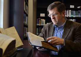 Ray Van Neste looks through a 1613 edition of the King James Bible that was recently donated to the Ryan Center for Biblical Studies. (Photo by Jacob Moore)