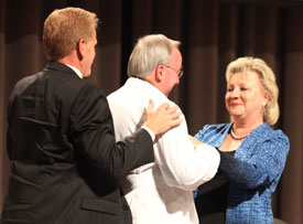 Sheila Mitchell (right), founding dean of Union's School of Pharmacy, and George DeMaagd (left), associate dean of academic instruction for the School of Pharmacy, present an honorary white coat to Union President David S. Dockery Aug. 21. (Photo by Kristi Woody)