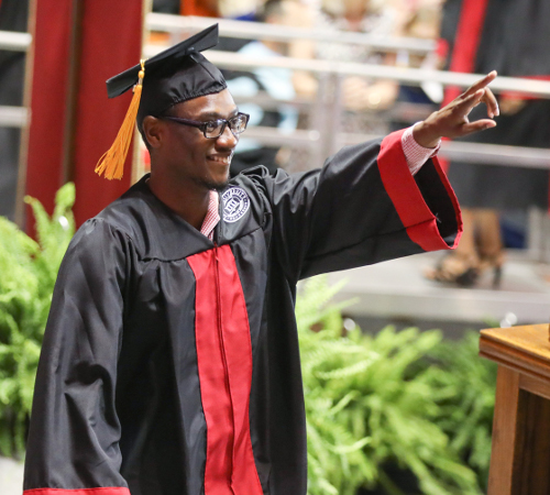 History major Cedric Davis walks across the stage at Oman Arena to receive his degree May 19. (Photo by Kristi Woody)