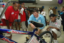 Chad Lewis (center), Union University LAUNCH student, talks with 11-year-old DeMond Mays (right) of Jackson about his new bicycle as Mays’ twin brother Deron looks on. The twins were among 21 children who received bicycles from the “Trikes for Tots” project Thursday night at the Salvation Army.