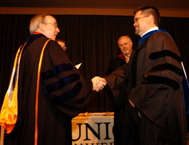 President David S. Dockery congratulates math and computer science professor Chris Hail, who was named Faculty Member of the Year at the Awards Day chapel service. (Photo by Morris Abernathy)