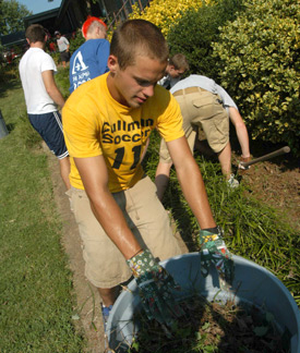 Michael Pugh, a sophomore soccer player at Union, helps remove weeds around a Jackson house Friday, Aug. 19. (Photo by Morris Abernathy)