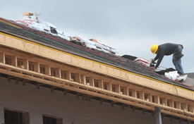 A construction worker adds shingles to the roof of one of the student housing buildings. (Photo by Morris Abernathy)