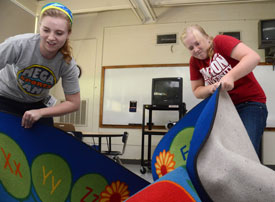Union senior Elissa Weber (left) and sophomore Emily Maggard deliver large reading rugs to classrooms at the old Lloyd Wood Middle School in Tuscaloosa, the temporary home to Holt Elementary School following an April tornado. (Photo by Beth Spain)