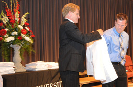 George DeMaagd, associate dean of the School of Pharmacy, presents a white coat to Darren Awender during a special Aug. 27 ceremony celebrating the launch of Union's pharmacy program. (Photo by Morris Abernathy)