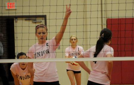 Ashley Young (5) calls the play while Katie Adams (1) gets set to serve. - Photo by Morris Abernathy