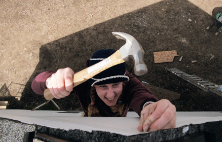 Kiera Knappman nails vinyl siding to the peak of a Habitat for Humanity home during GO Battle Creek. - Photo by Justin Veneman