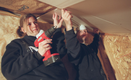Amy Edge and Sam McMinn hang drywall in the attic of a Battle Creek Habitat for Humanity home. - Photo by Justin Veneman
