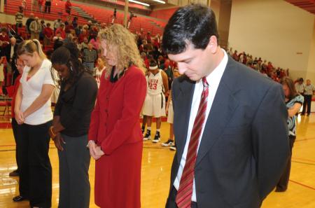 The Union coaching staff bows in prayer during the invocation.  From left to right is Melissa Cook, graduate assistant; Brianna Rawls, student assistant; Katie Woodruff, assistant coach; Mark Campbell, head coach. - Photo by Morris Abernathy