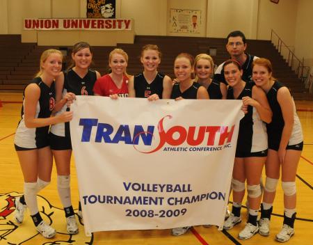 The Union volleyball team gathers around their TranSouth Conference Tournament Championship banner. - Photo by Morris Abernathy