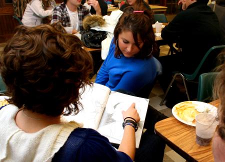 Senior art majors Alanna Taylor and Ellen Kay look through Kelsey Robert's sketchbook at the annual art retreat. - Photo by Kristi McMurry Woody