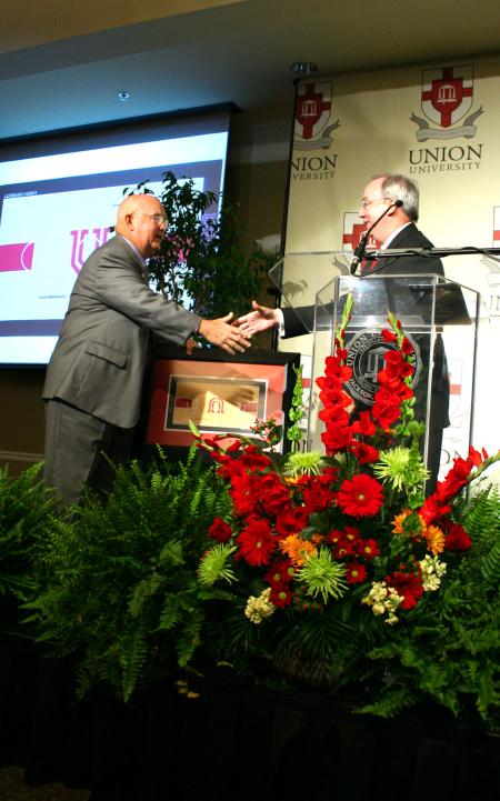 President Dockery presents David Blackstock with a framed print of what the new gym floor will look like.  The floor will be redone in honor of Blackstock, Union's former coach and athletic director. - Photo by Kristi McMurry Woody