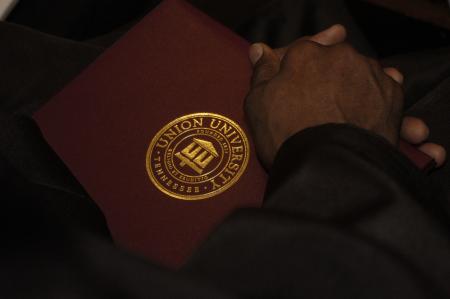 A graduate holds his newly, earned diploma during the fall graduation ceremony. - Photo by Beth Spain