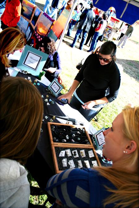 Rose Rogers, senior art major, takes orders for her handmade rings and other jewelry at Arts in the Park. - Photo by Kristi McMurry Woody