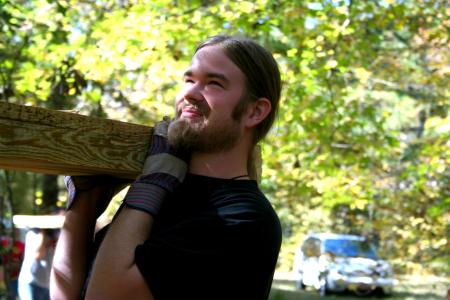 Travis Lutz, sophomore political science major, helps carry a heavy cedar plank to a drop-off point along the walking trail under construction at Pinson Mounds during Day of Remembrance. - Photo by Kristi McMurry Woody