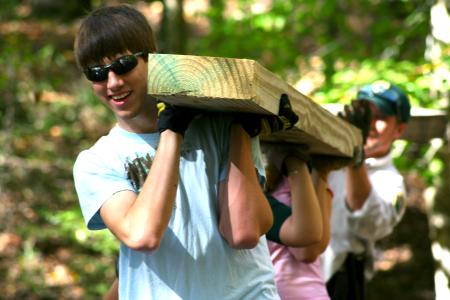 Chad Keathley, junior theology major, helps to carry a cedar plank for placement in the construction of a simple bog bridge at Pinson Mounds. - Photo by Kristi McMurry Woody