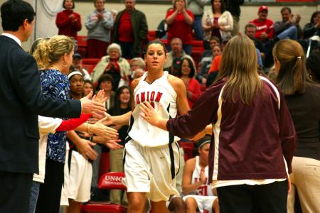 Kaitlin Dudley, junior physical education and health major, runs out to the cheers of fans and teammates at the start of the third game of the Rotary Classic.  - Photo by Kristi McMurry Woody