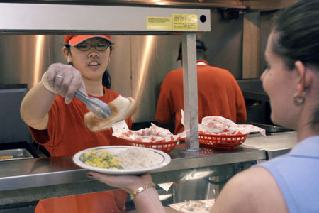 Junior Bambi Chao fills in for cafeteria employees unable to come to work because of tornado damage.
 - Photo by Jim Veneman