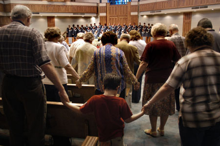 Community members joined hands across the aisles during prayer at the citywide prayer service held at First Baptist Church, Jackson. - Photo by Jim Veneman