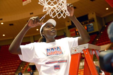 Josephine Owino cuts down a piece of the net at Oman Arena after winning the 2009 NAIA championship. - Photo by Kristi McMurry Woody