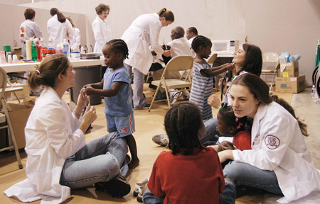 Debbie Garland checks Robert Bowman's blood pressure (background) as Erin Kay, Lauren Murphy and Carlyn Reeves provide comfort and welcome distraction to the children of Jackson's tornado victims. - Photo by Jim Veneman