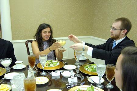 Melissa Jepsen, junior teaching English as a second language major, passes the salad dressing to Zachary Pendergrass, coordinator of career planning and development, at the 2009 Etiquette Luncheon. - Photo by Kristi McMurry Woody