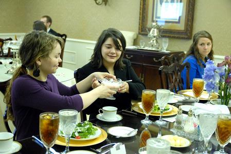 Tiffany Fredericks, senior French major, passes the salad dressing to Brandy Hudgins, career services secretary, during the 2009 Etiquette Luncheon. - Photo by Kristi McMurry Woody