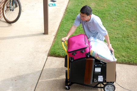 Don Van, professor of Engineering, rolls a cart of belongings to a student's room on freshman move-in day. Many faculty, staff, and students pitched in to help the freshmen move into their rooms. - Photo by Kristi McMurry Woody