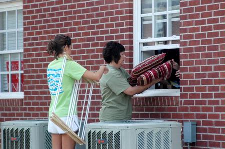 Senior Sara Greenlee and her mother Tina Greenlee strategically move into her room in the Quads through the back window. - Photo by Beth Spain