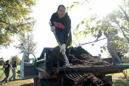 Ashley Nabors, senior nursing major, shovels mulch around a tree at Liberty Park during Campus and Community Day. - Photo by Beth Spain