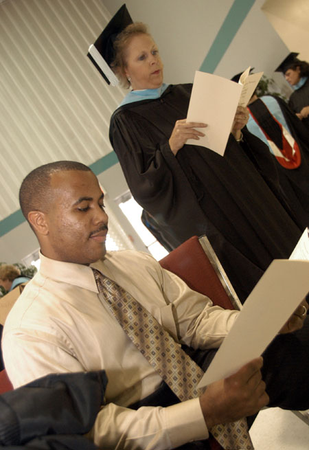 Germantown Education Specialist graduates Michael Lowe (seated) and Debbie Rudzena go over the program for the August 2003 commencement exercises shortly before the ceremony begins. - Photo by Jim Veneman