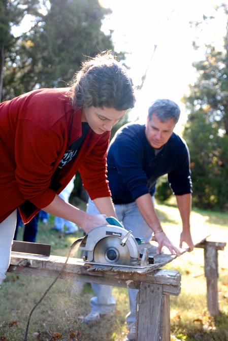 Megan Winters, sophomore history major, cuts a piece of wood as David Thomas, professor of history, holds the board down. The wood is used as part of a building project completed by the history department for Campus and Community Day.  - Photo by Kristi McMurry Woody