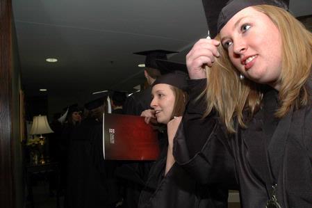 Joanna Sparks, Spanish graduate, and Jessica Vanderpool, ournalism graduate, adjust their caps and hair in the reflection of a glass case before Union's fall graduation ceremonies begin. - Photo by Beth Spain
