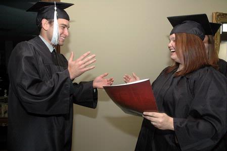 Wagner Oliveira, DMS-Art graduate, and Amanda Middleton, Art graduate, practice shaking hands with President Dockery before Union's fall graduation ceremony begins. - Photo by Beth Spain