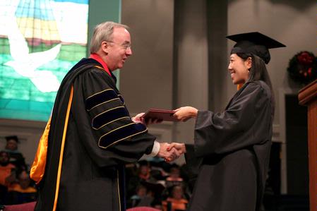 Jan Dui Kim receives her bachelor of science in chemistry from President Dockery at the fall graduation ceremony. Kim also received the Academic Excellence Medal for a major in chemistry. - Photo by Kristi McMurry Woody