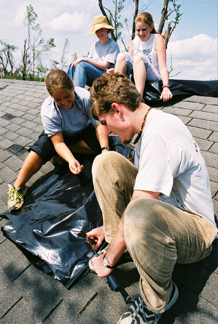 Jennifer Winfield, Lindsay McBride, Jennifer Kalinoski, and Josh MacDonald worked on a temporary fix for this roof which suffered damage from the May tornado that hit Jackson. - Photo by Kristen Hiller