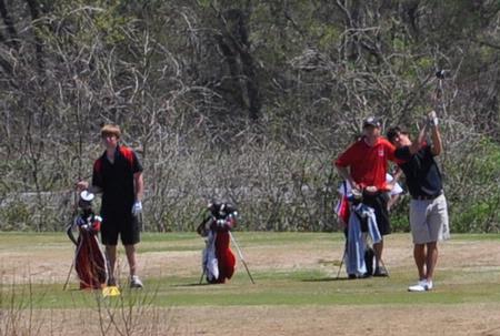 Jake Carroll tees off while Matt Kelley (far left) awaits his turn. - Photo by Steven Aldridge
