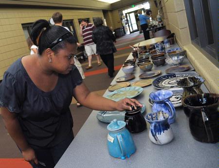 Carrie Myers, sophomore biology major, looks over some pottery at the annual Mother's Day Pottery and Art Sale where art students have an opportunity to sell their work.  - Photo by Morris Abernathy