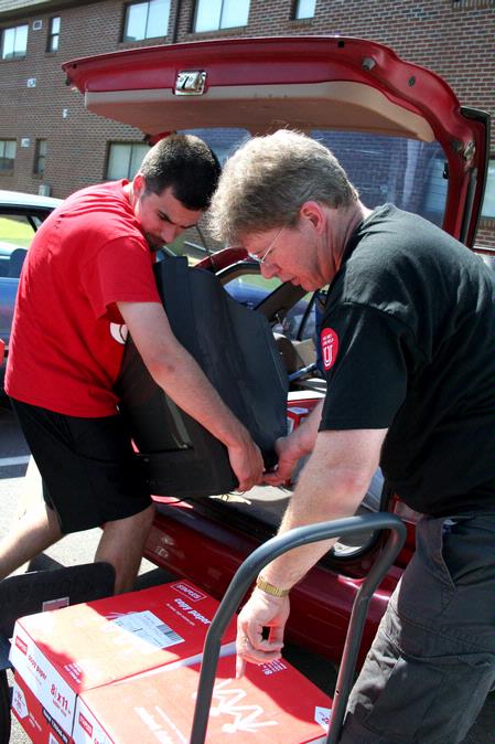 Mark Bolyard, professor of biology and department chair, and Eric Olson, junior engineering major, help a new student unpack her car of Move In Day. - Photo by Deanna Santangelo