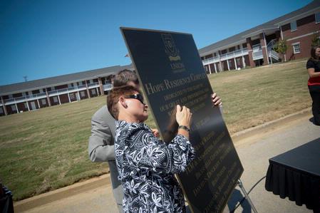 Melanie Rickman, executive secretary to the president, displays the commemorative plaque for the Hope Residence Complex in preparation for the dedication ceremony.  - Photo by Morris Abernathy