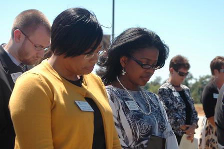 Zachery Pendergrass, Jacqueline Taylor, and Renee Jones bow in prayer during the dedication of the Hope Residence Complex.  - Photo by Beth Spain