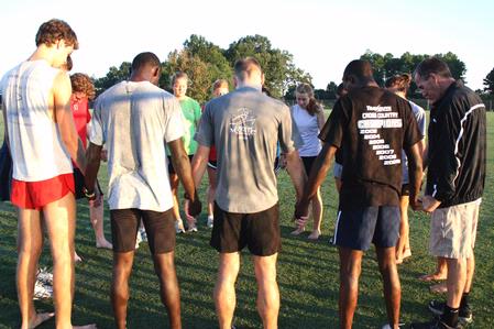 Coach Gary Johnson leads the Union Cross Country team in prayer after a morning practice. - Photo by Ebbie Davis