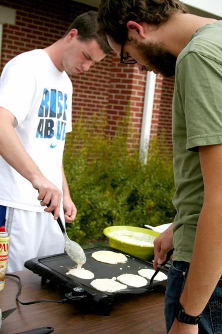 Sam Dahl, senior Christian ethics major, and Zac Settle, junior philosophy major, cook the pancakes that will later be used for the pancake eating contest during the Watters Great Outdoors event. - Photo by Deanna Santangelo