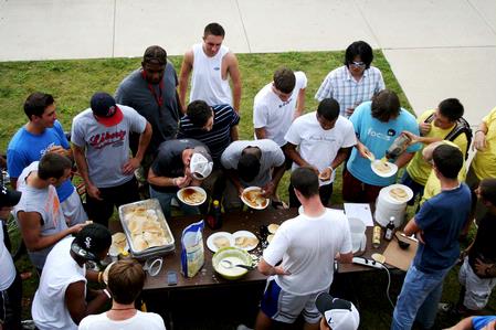 The men of the Watters quad gather around a table to cheer on their teammates who are competing in the pancake eating contest at the Watters Great Outdoors competition. - Photo by Deanna Santangelo