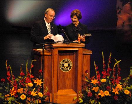 David S. Dockery, president of Union University, presents Laura Bush, former first lady of the United States, with gifts bearing significance to Union. Dockery presented a study Bible, to which several Union faculty contributed, and a Lady Bulldogs baseball cap, representing Union's national title in women's basketball. - Photo by Victoria Stargel